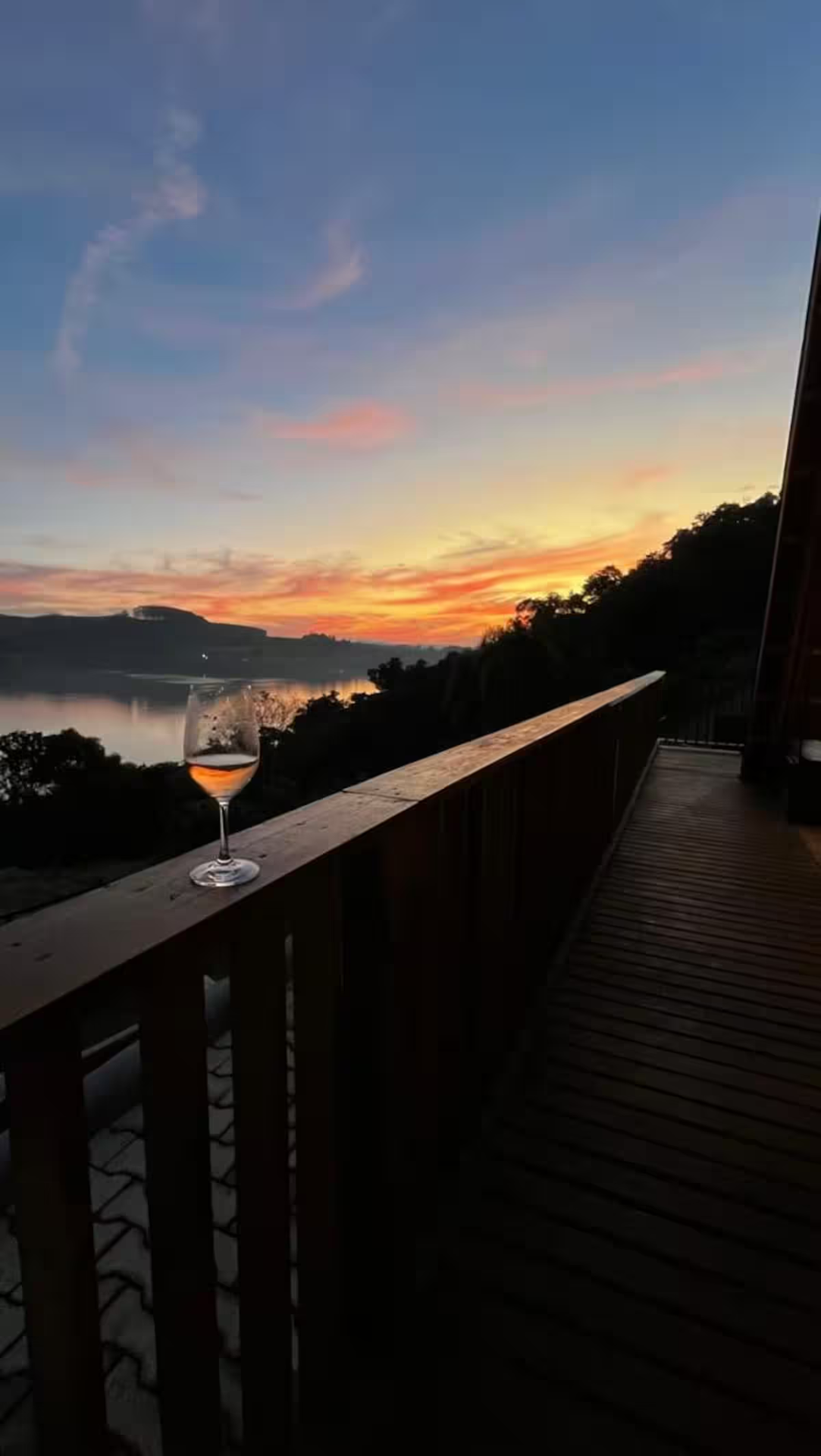 Vista do deck do chalé para o lago ao pôr do sol